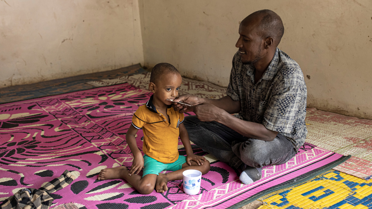 A man feeds his son during a screening for malnutrition at Locher Angamor Health Dispensary in Kakuma Refugee Camp, Turkana, Kenya.